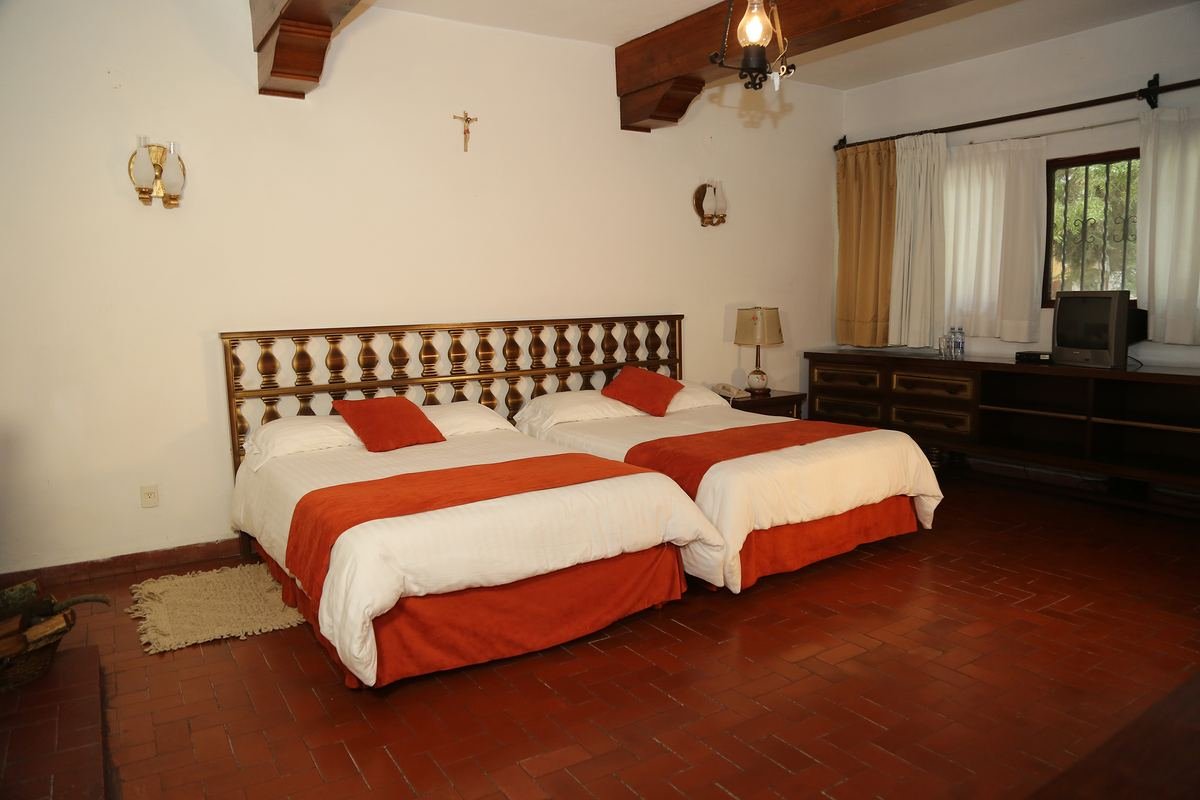 Habitación Hacienda con dos camas matrimoniales y vigas de madera