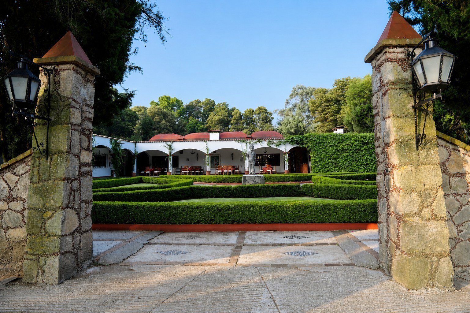 Plaza de acceso a la hacienda con jardines y portón de piedra