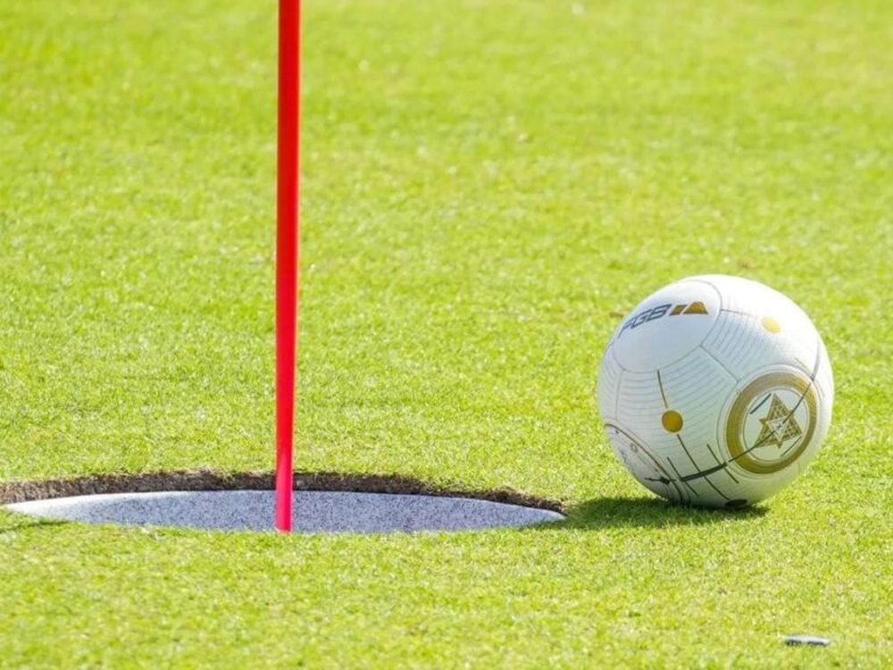 Footgolf: balón junto al hoyo con bandera en el campo de golf